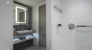 Ein modernes Badezimmer mit einem großen Spiegel, einem Waschbecken, einer Badewanne und einer Dusche.