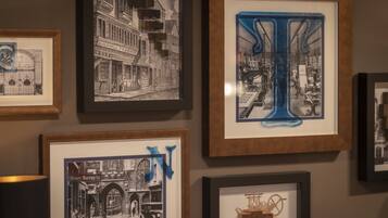 A wall with multiple framed artworks, including black and white photographs and a colorful abstract piece.