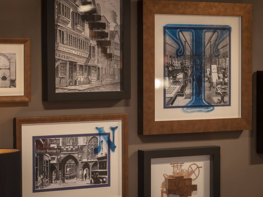 A wall with multiple framed artworks, including black and white photographs and a colorful abstract piece.