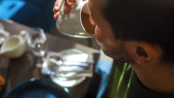 A person sitting at a table with a plate of food and a cup.