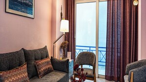 Ein modernes Wohnzimmer mit Sofa, Sesseln, einem Couchtisch und einem Balkon mit Vorhängen.