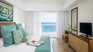 A hotel room with a bed, a TV, a dresser, and a view of the ocean. - Mayan Palace Acapulco (Acapulco, Guerrero)
