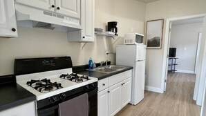 A kitchen with white cabinets, a stove, a microwave, and a refrigerator.