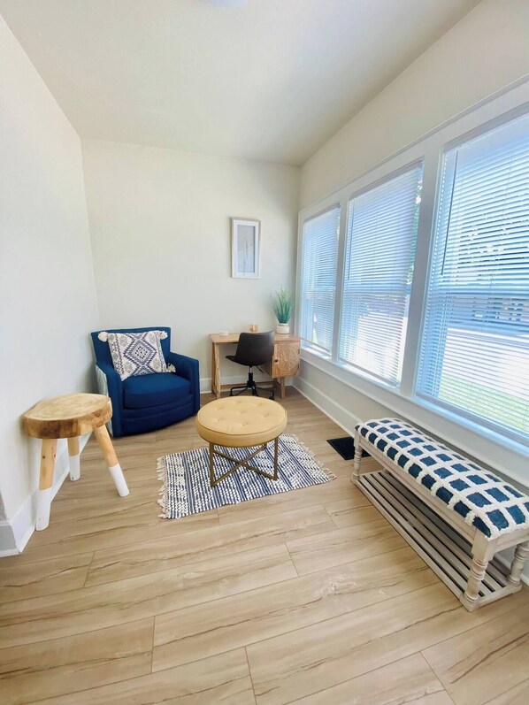A living room with a blue sofa, a round table, a bench, and a wooden floor. - The Tiny Piney - Live. Work. Play. Downtown Green Bay! (Green Bay)