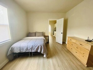 A bedroom with a bed, a dresser, and a window. - The Tiny Piney - Live. Work. Play. Downtown Green Bay! (Green Bay)