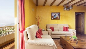 A living room with a balcony, a sofa, a wooden coffee table, and a painting on the wall.