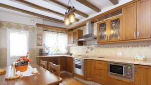 A kitchen with wooden cabinets, a stainless steel oven, a microwave, and a hanging light fixture.