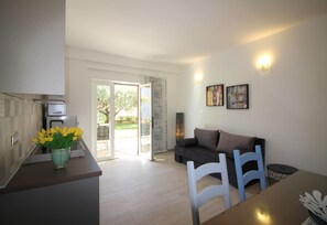 A modern kitchen with a dining area, a sofa, and a table with chairs.
