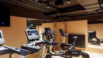 Un gimnasio con diversas máquinas de ejercicio, incluyendo cintas de correr y elípticas.