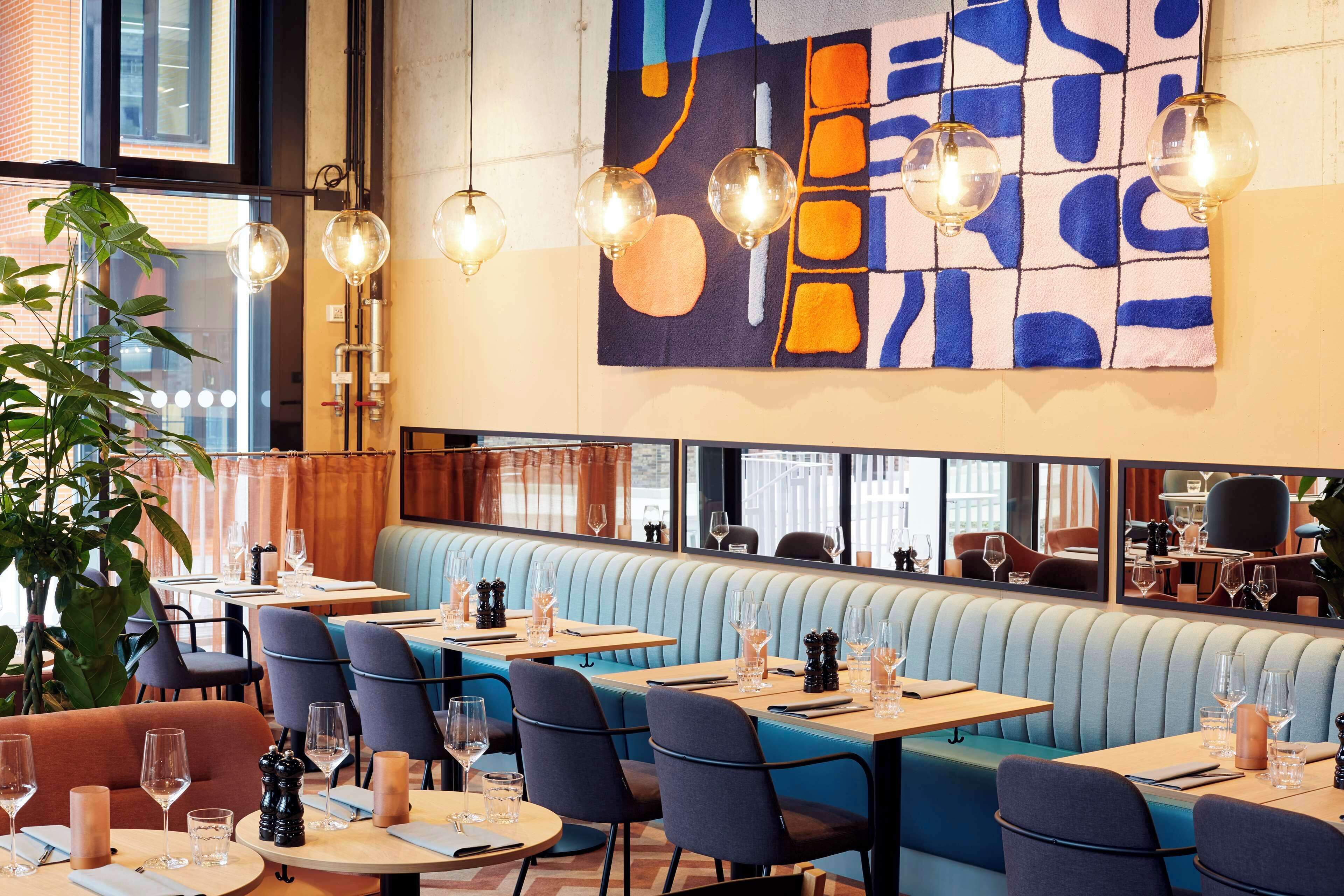 Un restaurante con cabinas, mesas redondas e iluminación colgante.