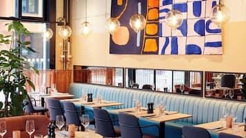 Un restaurante con cabinas, mesas redondas e iluminación colgante.