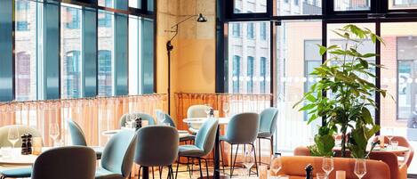Un restaurante con amplios ventanales, sillas modernas y una planta en maceta.