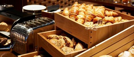 Un buffet proposant une variété de produits de boulangerie, notamment des croissants et des viennoiseries.