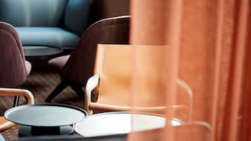 Un área de estar moderna con un sofá azul, un sillón marrón y una pequeña mesa redonda.