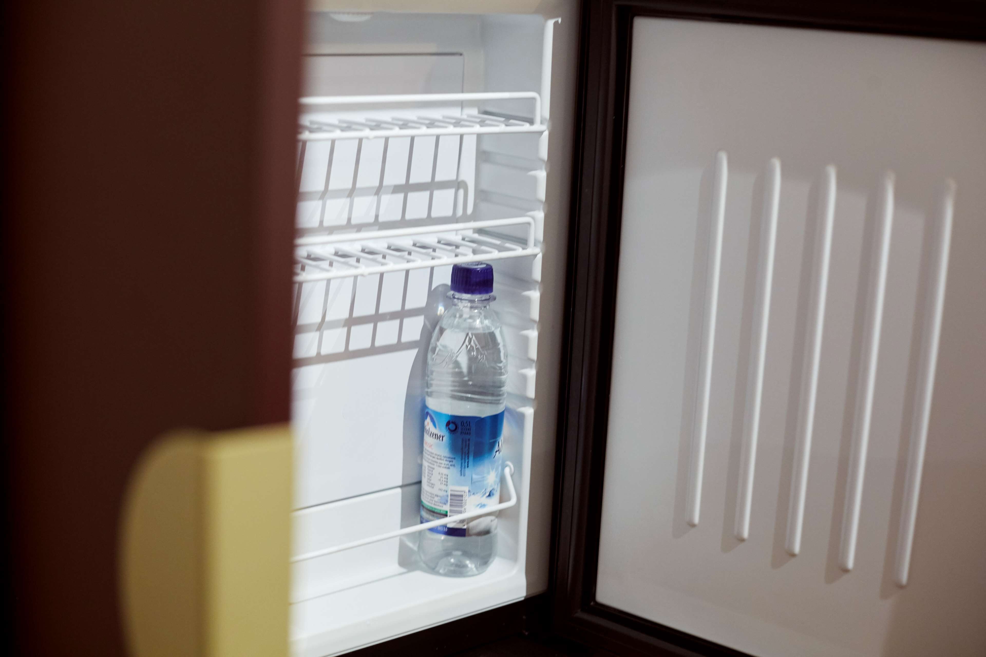 Een koelkast met meerdere planken en een fles water op de onderste plank.