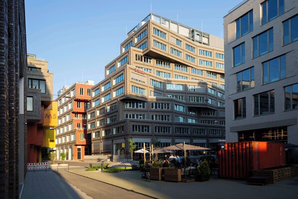 A multi-story building with a modern architectural design, featuring a mix of brick and glass facades. - Scandic München Macherei (Munich)
