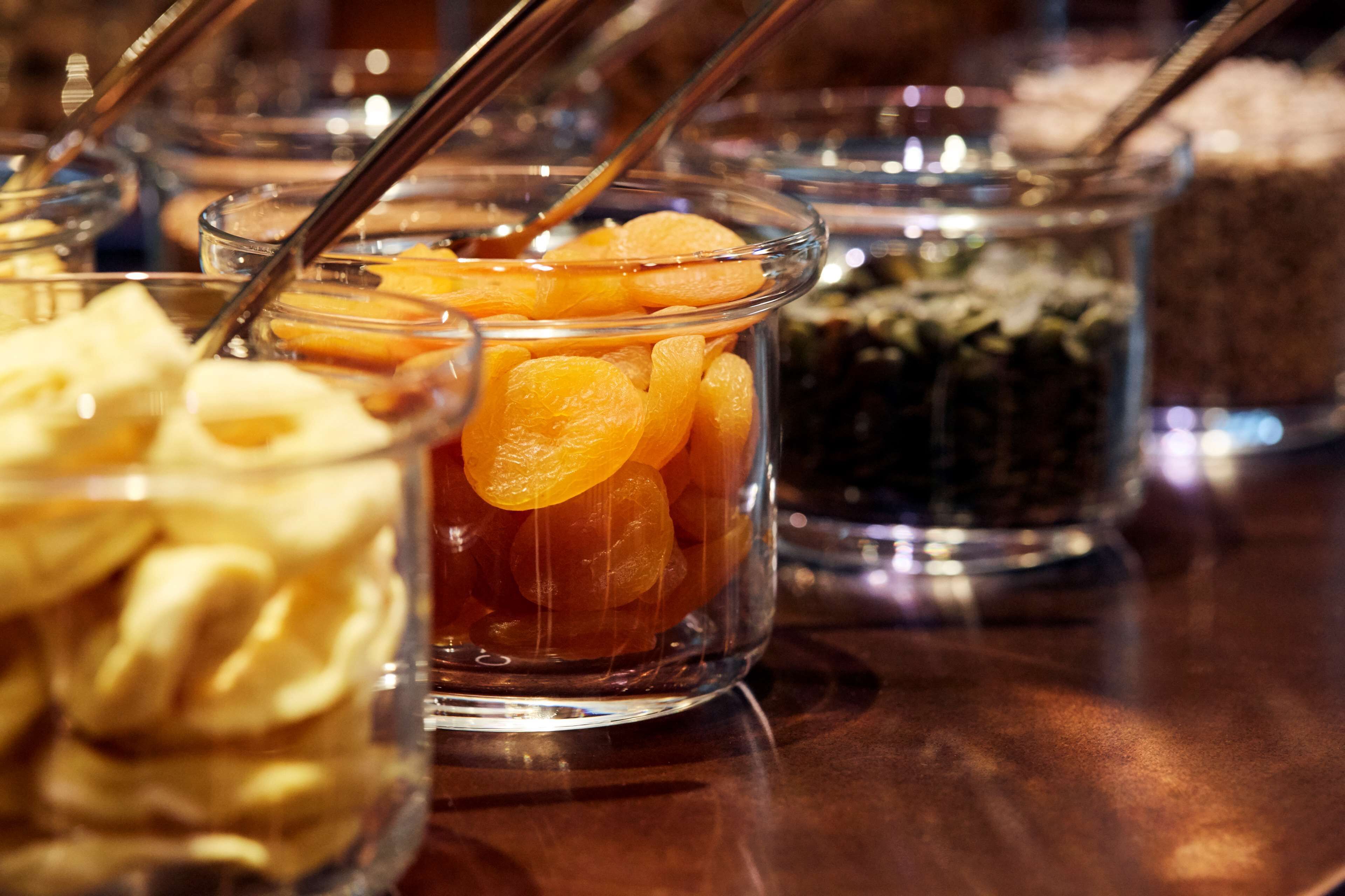 A buffet with various food items in glass containers, including what appears to be dried fruits and other snacks.