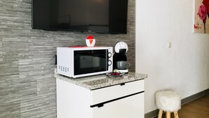 A compact kitchenette with a microwave, coffee maker, and a small stool. - Alcazar by Interhome (Saas-Grund)