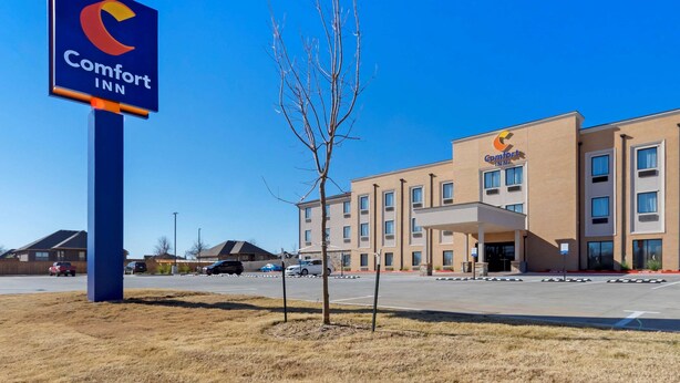 A Comfort Inn hotel with a clear blue sky, a parking lot, and a simple building facade.