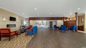 A spacious lobby with a wooden floor, seating areas, a reception desk, and a mounted TV. - Comfort Inn & Suites Harrah (Harrah)