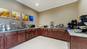 A kitchen with wooden cabinets, a granite countertop, and various appliances including a coffee maker and toaster.