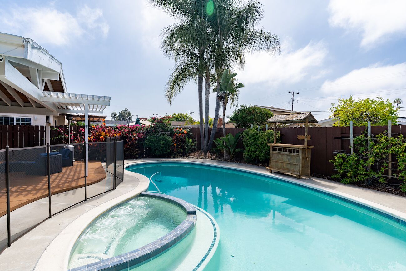 Una piscina con hidromasaje, rodeada por una terraza de madera y un patio amurallado.