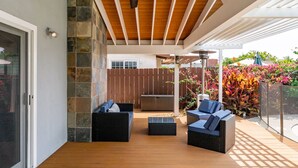 Ein überdachter Patio-Bereich mit Korbmöbeln und Deckenventilator.