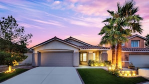 A residential house with a garage, a well-maintained lawn, and a palm tree.