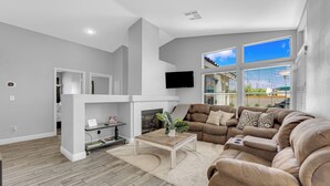 A modern living room with a sectional sofa, a fireplace, and a large window with a view.
