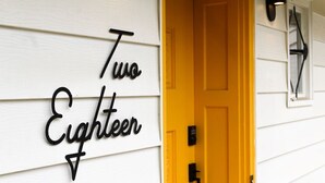 Un bâtiment blanc avec une porte jaune et une enseigne sur laquelle on peut lire « Two Eighteen ».
