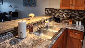 Cocina moderna con encimeras de granito, pileta de acero inoxidable y muebles de madera.