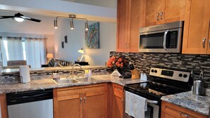Una cocina moderna con armarios de madera, un microondas de acero inoxidable y una estufa negra.