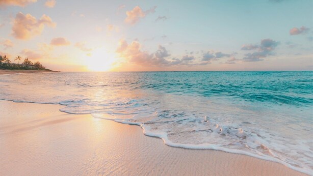 Una playa con olas suaves y un atardecer.