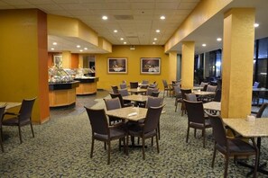 A hotel dining area with multiple tables and chairs, a buffet counter, and framed pictures on the walls. - Chicago Lake Shore Hotel (Chicago)