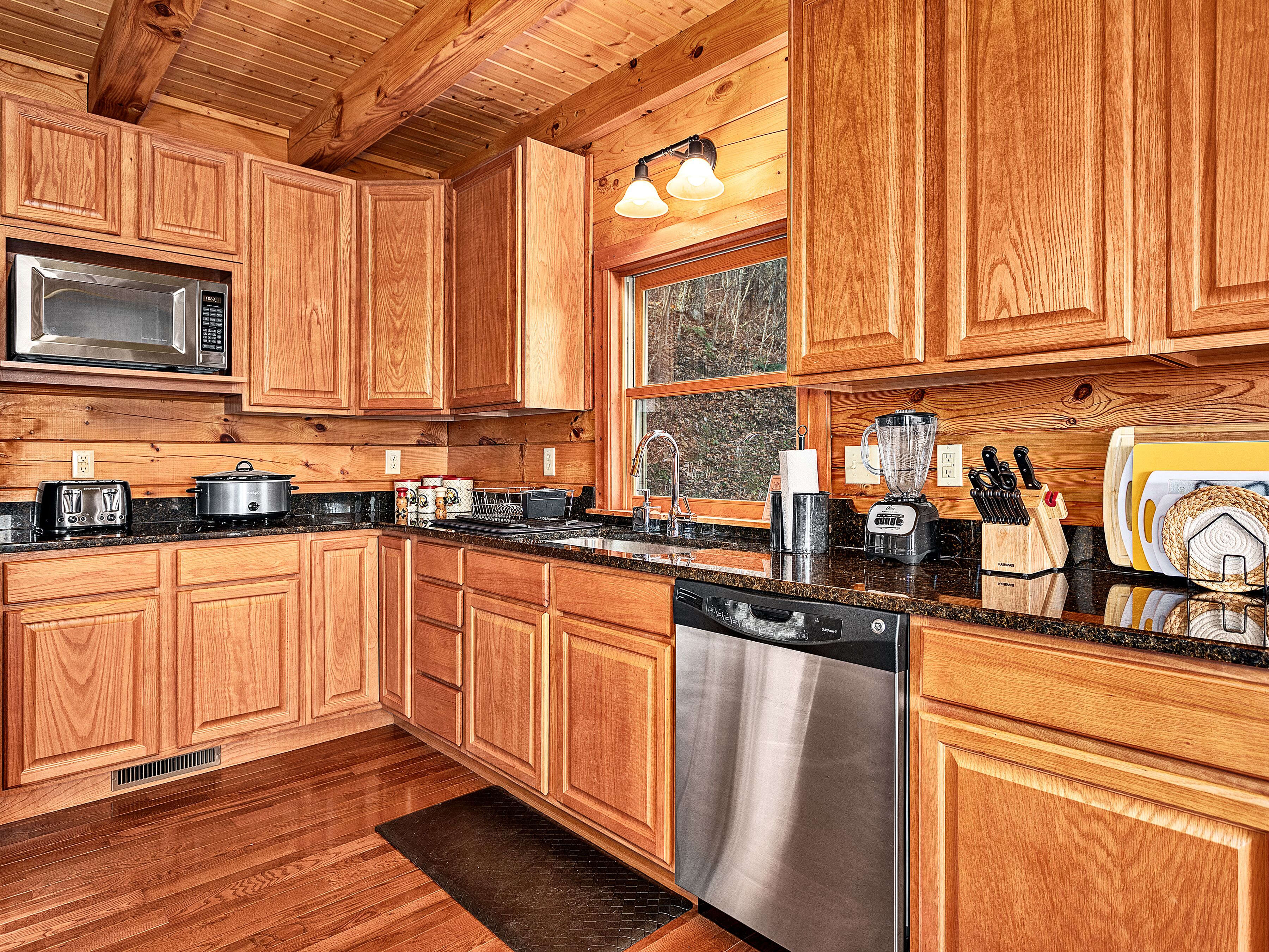 A kitchen with wooden cabinets, stainless steel appliances, and a window.