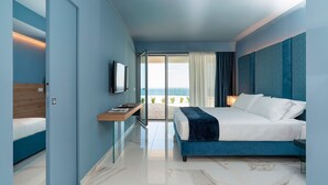 A modern hotel room with a bed, a desk, a TV, and a view of the beach. - Luxury villa with pool, sea view, 20 pax, Giardini Naxos, Sicily (Giardini-Naxos)