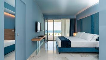 Ein modernes Hotelzimmer mit Bett, Schreibtisch, Fernseher und Blick auf den Strand.