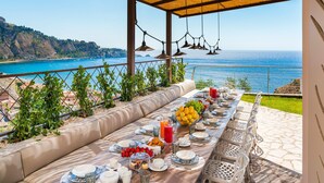 A table set for breakfast with a view of the sea and hills. - Luxury villa with pool, sea view, 20 pax, Giardini Naxos, Sicily (Giardini-Naxos)