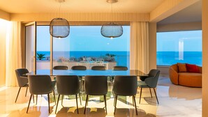 A modern dining area with a large table and chairs, large windows with a view of the ocean, and a cozy seating area with a sofa. - Luxury villa with pool, sea view, 20 pax, Giardini Naxos, Sicily (Giardini-Naxos)