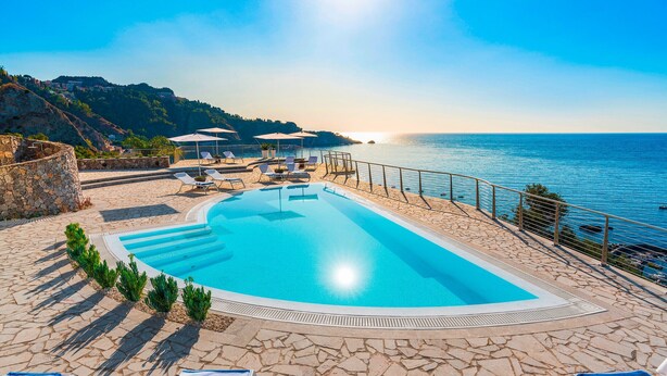 A swimming pool with lounge chairs and umbrellas, surrounded by stone flooring and a view of the sea. - Luxury villa with pool, sea view, 20 pax, Giardini Naxos, Sicily (Giardini-Naxos)