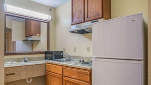Una cocina compacta con armarios de madera, un refrigerador blanco, un microondas y un lavamanos.
