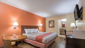 Una habitación de hotel con una cama, un escritorio, una silla y un televisor.