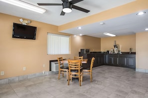 A spacious kitchen with a dining area, a ceiling fan, recessed lighting, and a flat-screen TV mounted on the wall. - Rodeway Inn and Suites Macon (Macon)