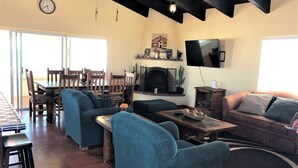 Una sala de estar con chimenea, televisor y comedor con muebles de madera.