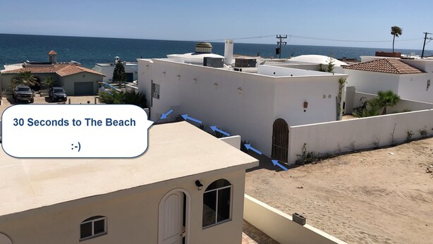 Zona residencial con edificios blancos, cielo azul despejado y vista al mar.
