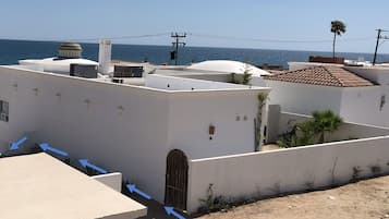 A residential area with white buildings, a clear blue sky, and a view of the sea.