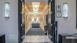 Vestíbulo de hotel con una recepción central, un muro estampado y tres ascensores.