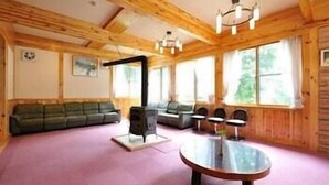 Ein gemütliches Blockhaus-Interieur mit Holzbalkendecke, einer Couch, einem Tisch und einem Kamin.