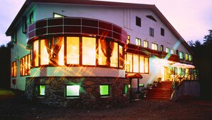 Ein zweistöckiges Haus mit Steinfundament, großen Fenstern und einer Veranda.