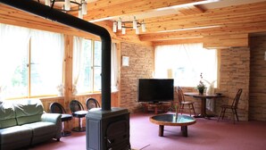 Ein gemütliches Wohnzimmer mit Holzvertäfelung, Kamin, Fernseher und Essecke.